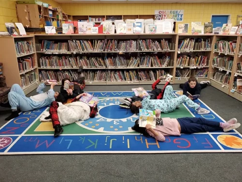 Group of students laying down and reading in the library.