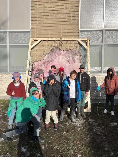 Students pose in front of a framed hide.