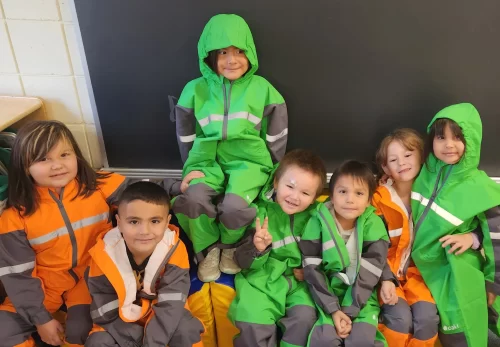 Young students in splashsuits pose in their classroom