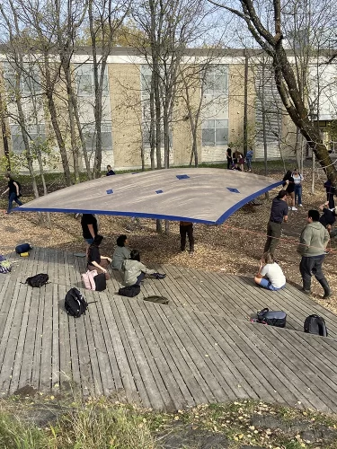 Setting up a large tarp roof at an outdoor ampitheatre.