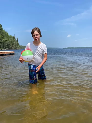 Special education student at the beach with a ball.
