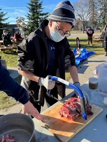 Special education student cuts meat with a bonesaw.