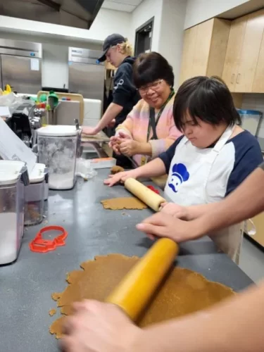 Special education student rolls out dough in a classroom.
