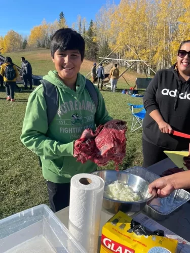 Student holds a large chunk of meat at Fall Harvest.